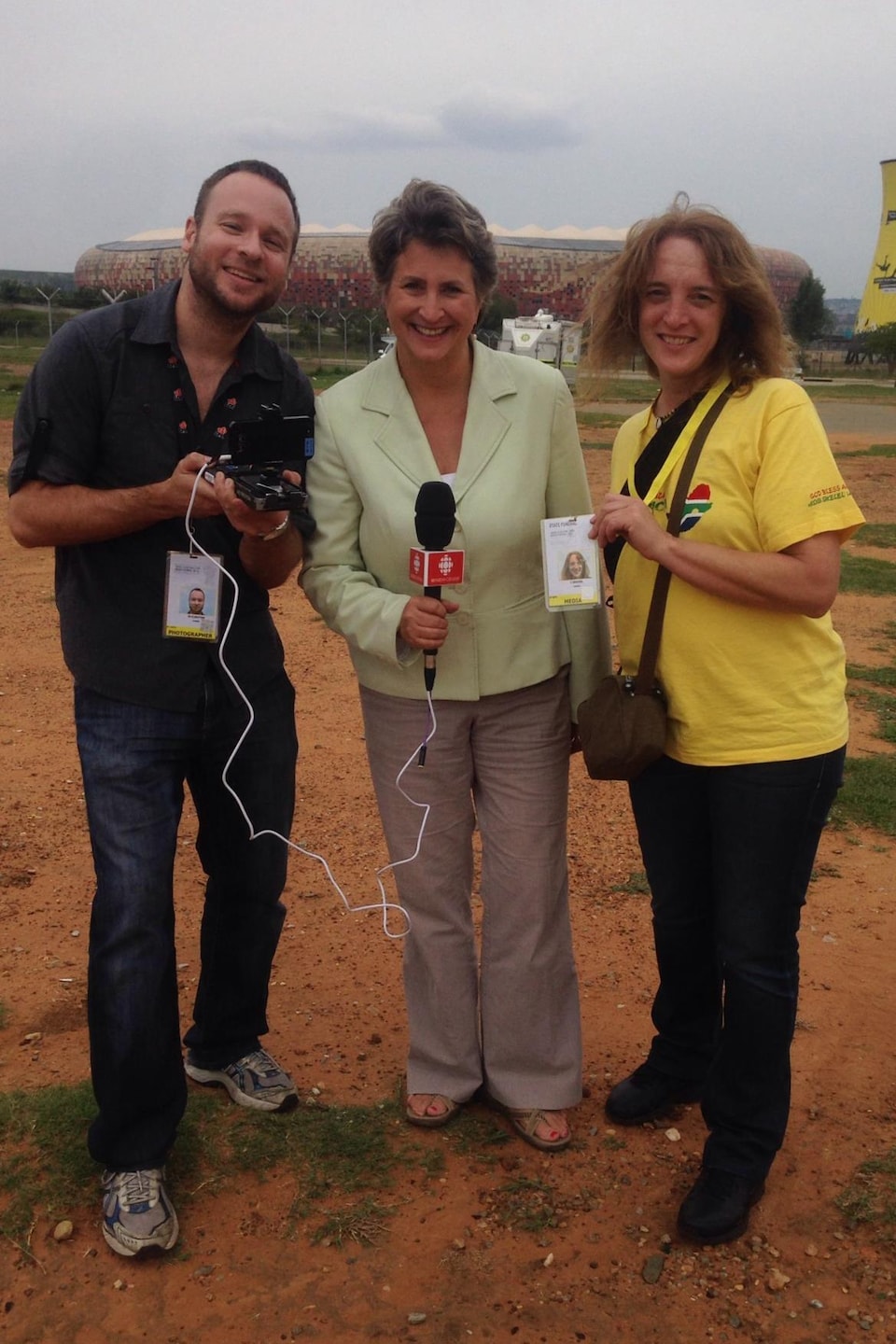 Le caméraman Martin Cloutier, la journaliste Sophie Langlois et l'assistante à la réalisation Louise Gravel, devant le stade de Soweto en Afrique du Sud.
