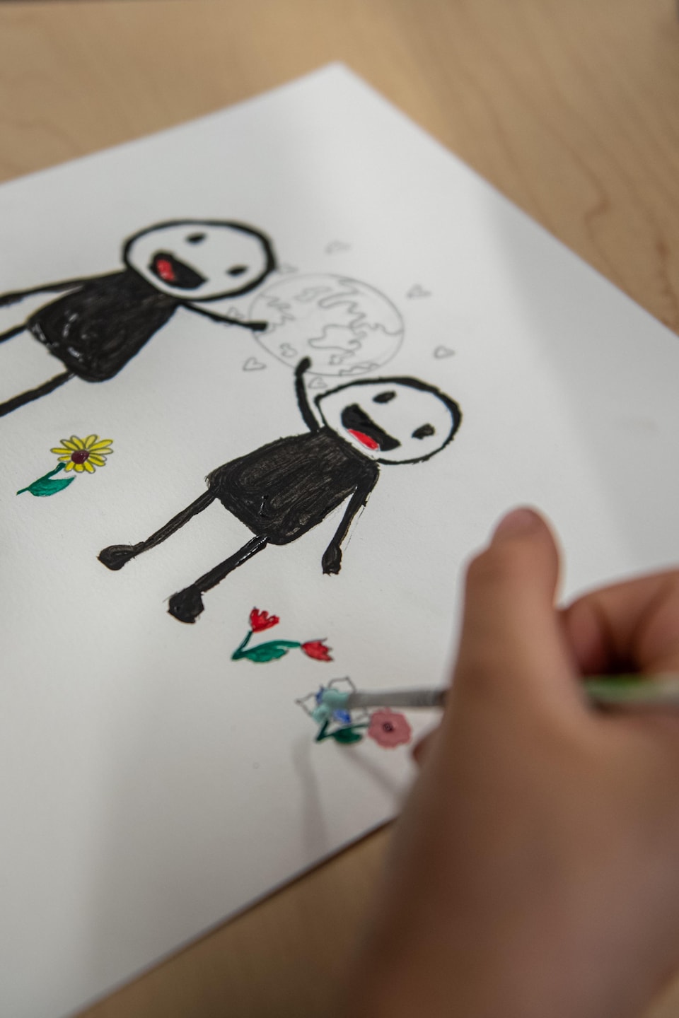 Une enfant peint une oeuvre à la manière d'Ultra Nan. Deux personnages tiennent une terre. 