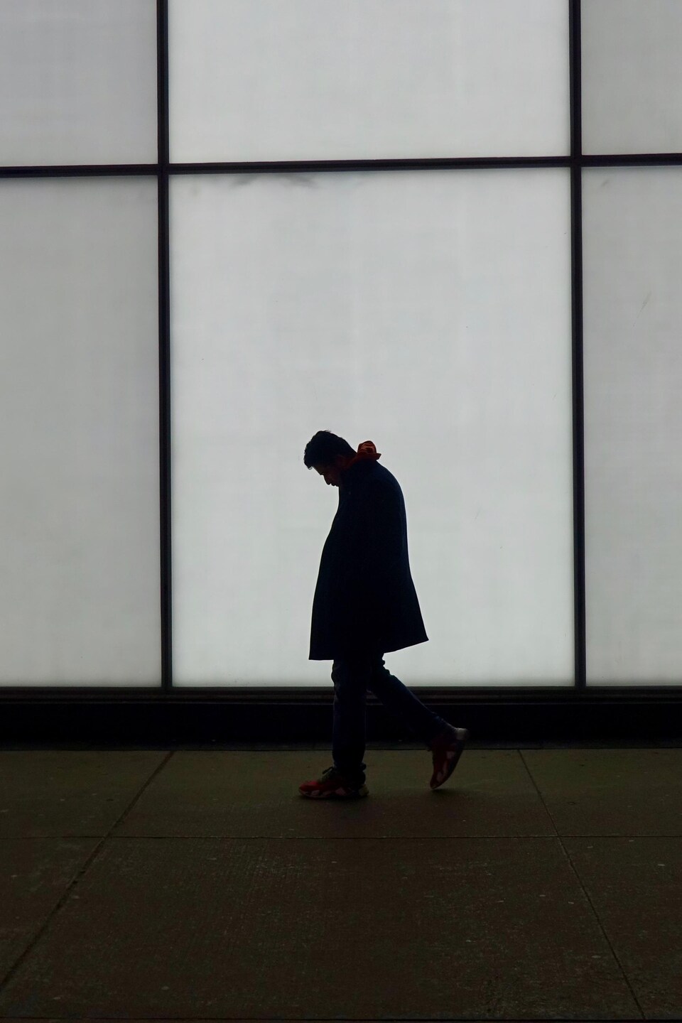 Un homme marche devant un mur lumineux.

                               