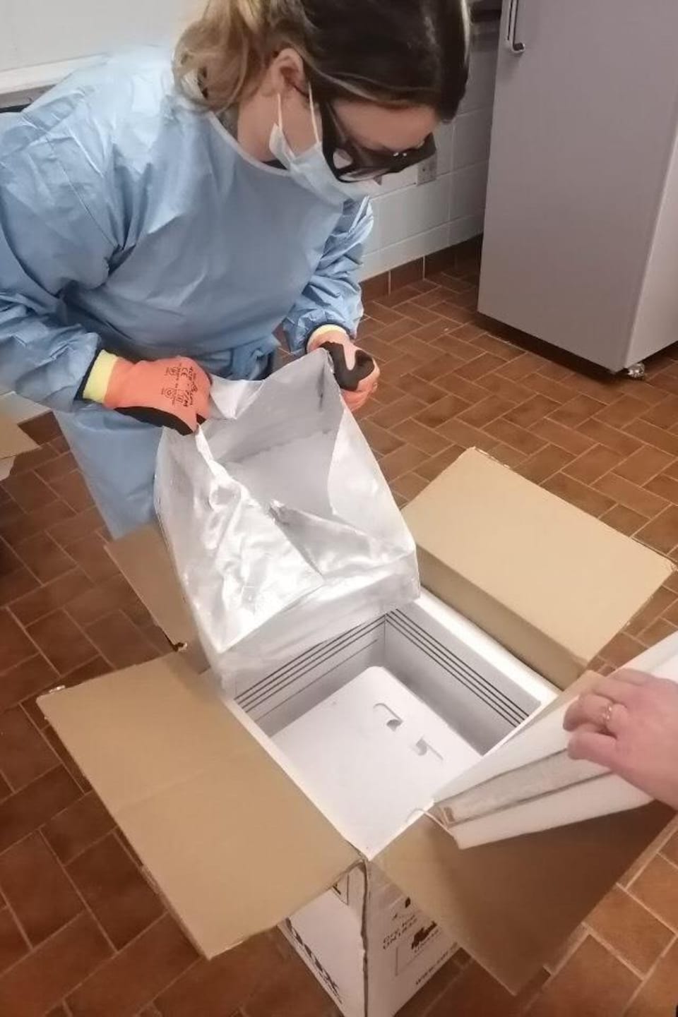 Ouverture d'une boîte de carton remplie de vaccin.