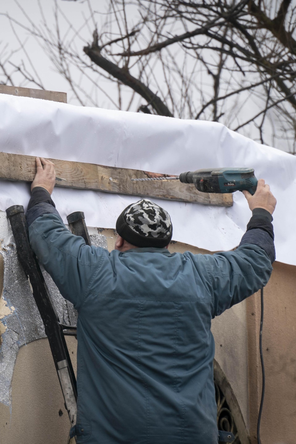  Un homme en Ukraine répare sa maison détruite par les Russes.