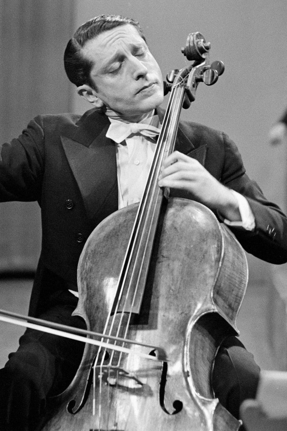 Walter Joachim jouant du violoncelle avec un orchestre en arrière-plan.