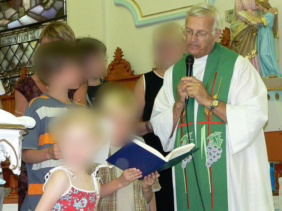 L’abbé Paul-André Harvey, avec des enfants, lors d'une cérémonie