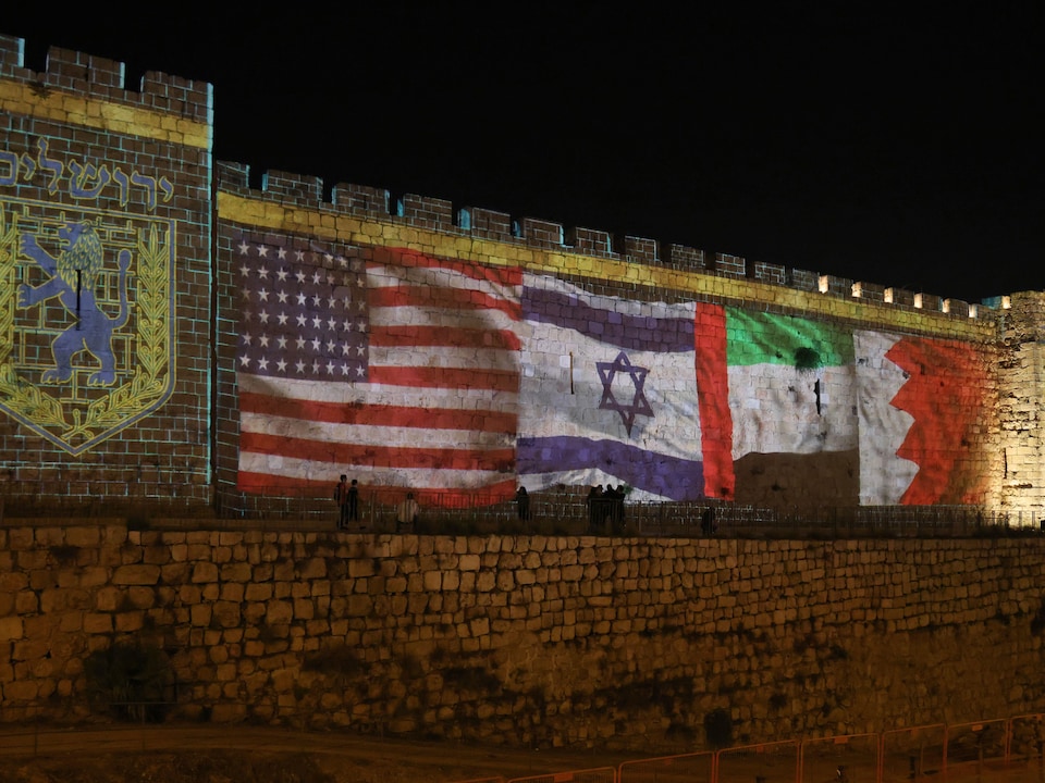 Les murailles de la vieille ville la nuit avec les drapeaux projetés dessus.