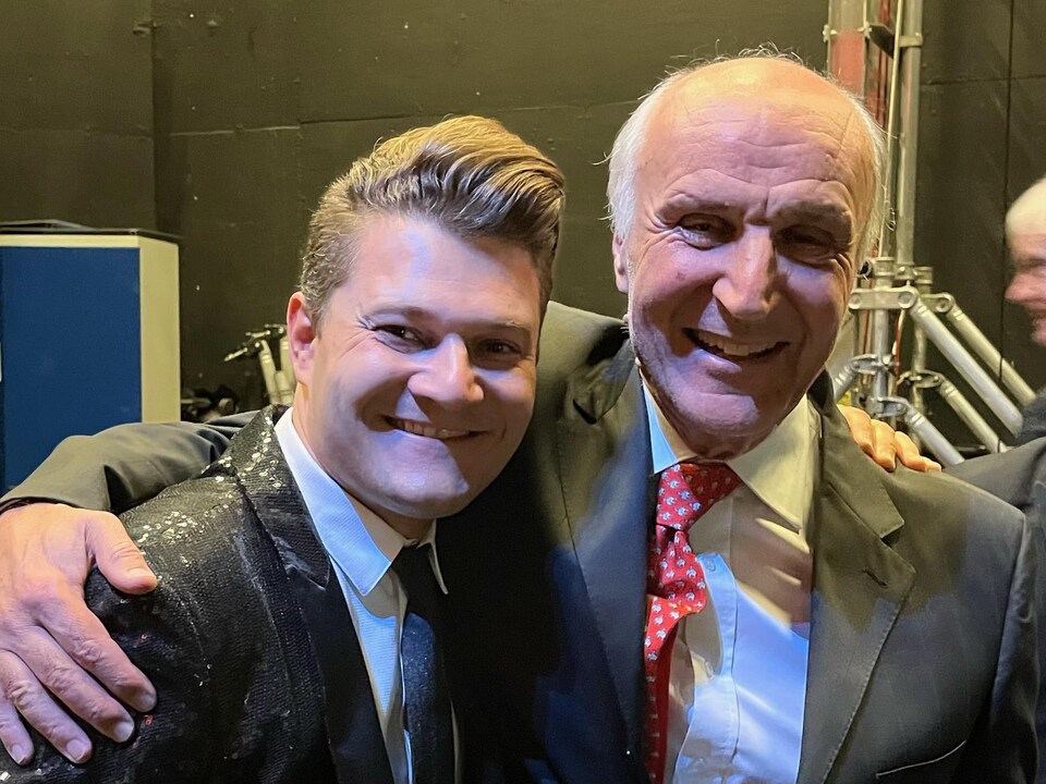 The two men hugged, smiling and in suits.