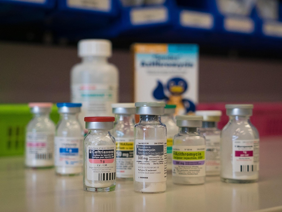 On voit en gros plan plusieurs flacons d'antibiotiques sur un comptoir de la pharmacie d'un hôpital.