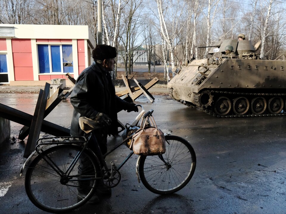Un homme passe près d'un char d'assaut avec un vélo.