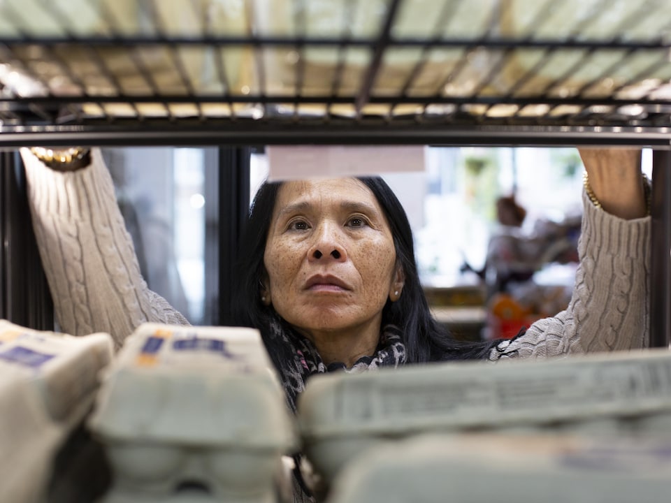 Une femme organise des cartons d'œufs dans un réfrigérateur.