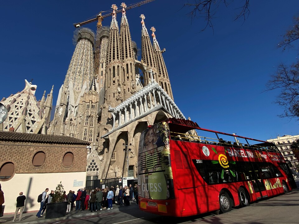 Un autobus touristique et des touristes devant la Sagrada Familia, à Barcelone.