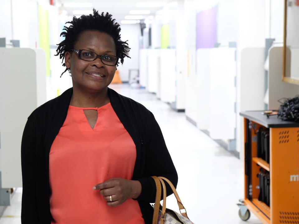 Bertine Kouadio debout souriante debout dans un couloir.