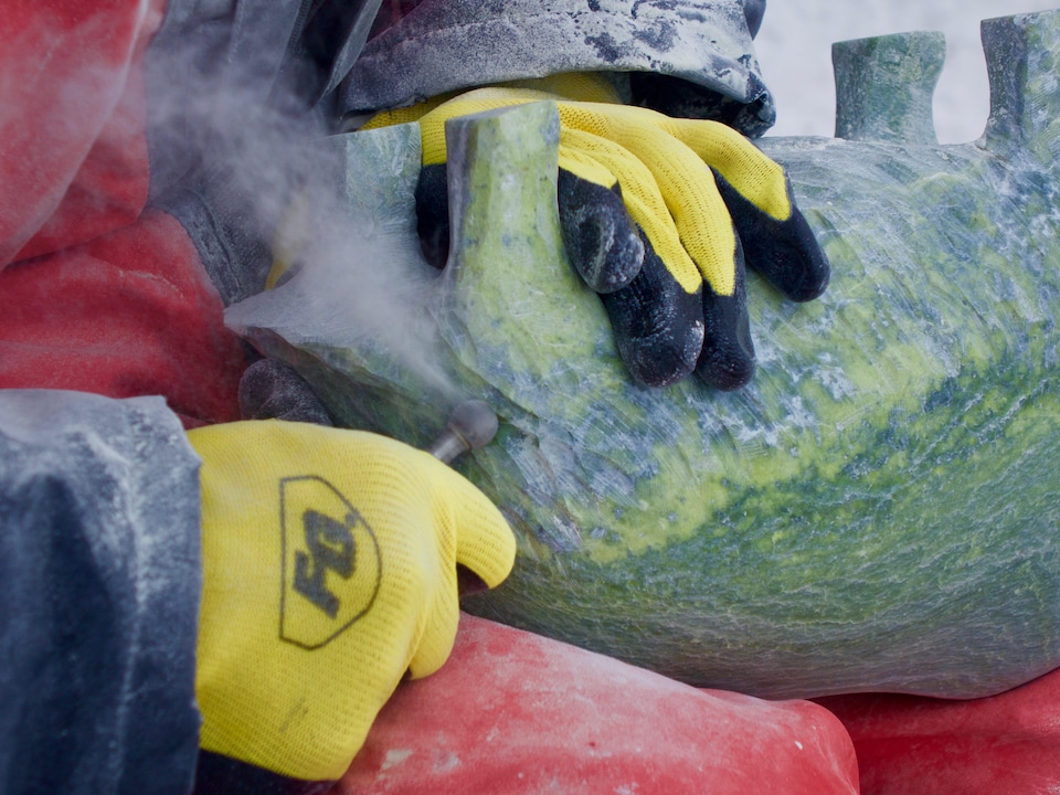 Une image des mains de Jomie Aipeelee alors qu'il définit les courbes du boeuf musqué. Cette oeuvre est sculptée dans la pierre de serpentine.