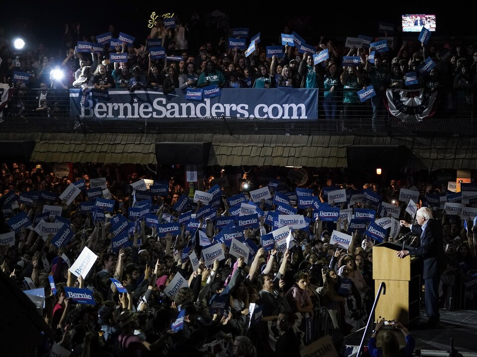 Une foule en liesse acclame Bernie Sanders, qui est sur scène. 