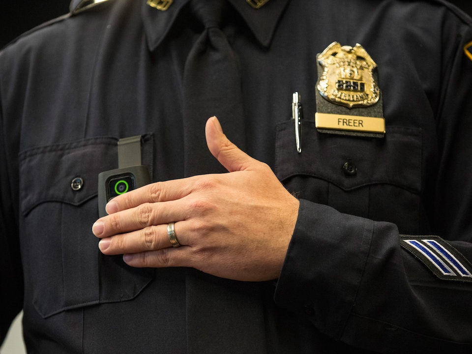 Close-up of an intervention camera hanging from the torso of a uniformed policeman.