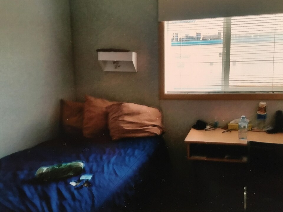 Un lit et un bureau près d'une fenêtre dans une petite chambre. 