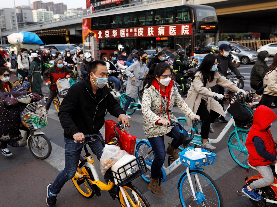 Des personnes portant des masques de protection sur leur vélo à Pékin le 7 avril 2020. 