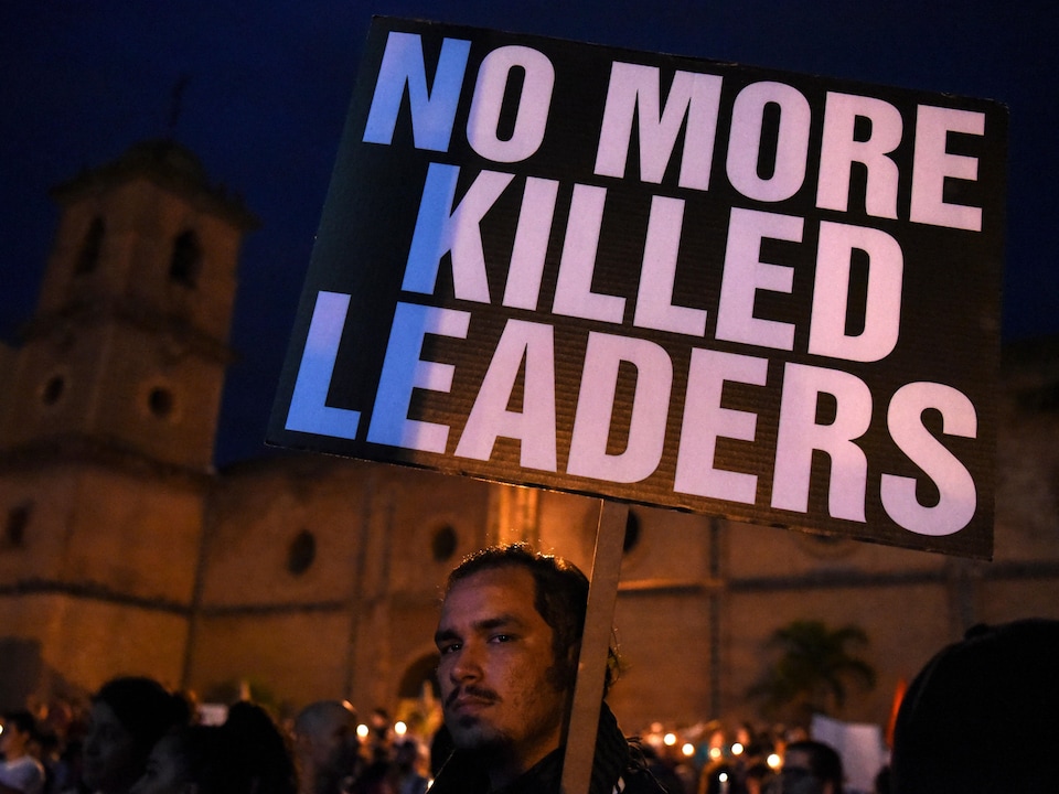 Un homme tient une pancarte sur laquelle il est écrit : « Plus d'assassinats de leaders ».