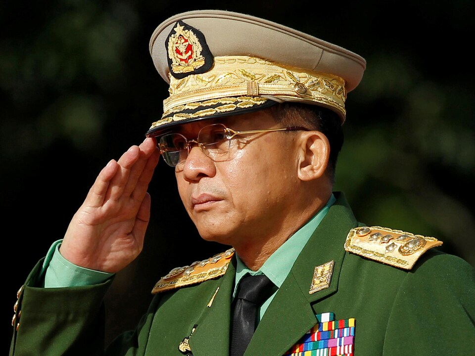Le général, vêtu d'un veston couvert d'écussons, fait le salut militaire.