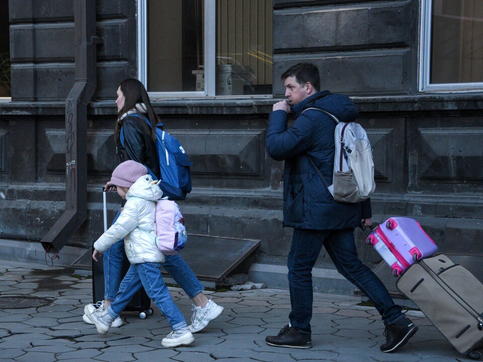 A couple and a little girl are hauling luggage.