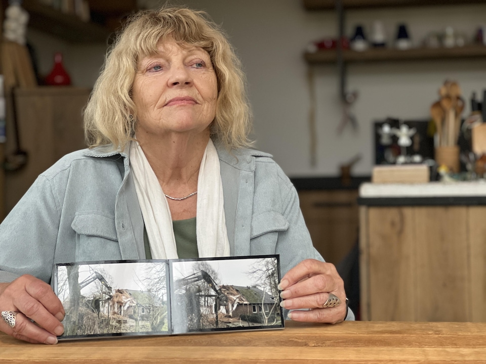 Corinne Johnson heeft twee foto's in zijn handen waarop een opgraving te zien is waarbij zijn huis wordt gesloopt. 