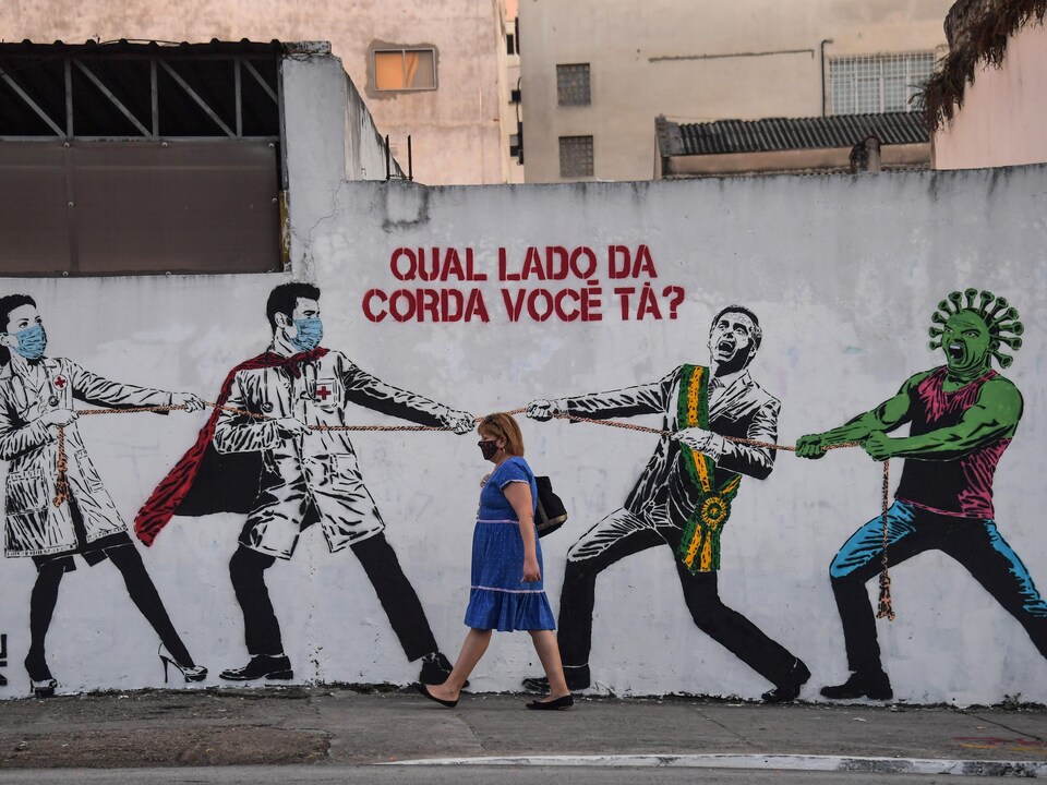 Une femme masquée passe devant le graffiti.