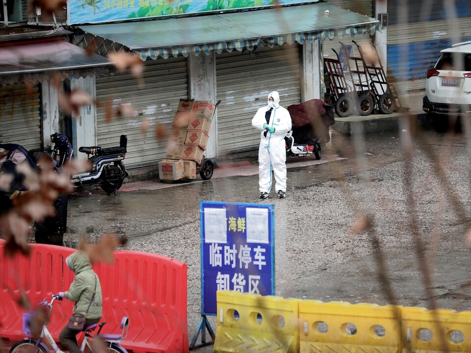 Un homme en tenue de protection au milieu du marché, dont les étals sont fermés.