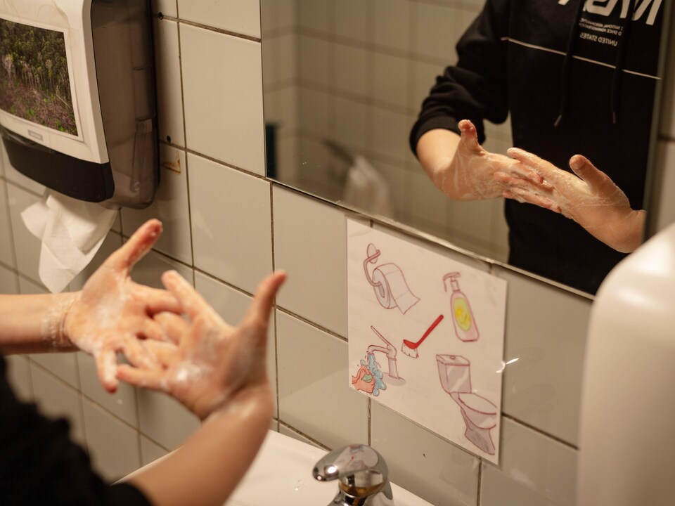 Un enfant se lave les mains soigneusement devant un miroir.