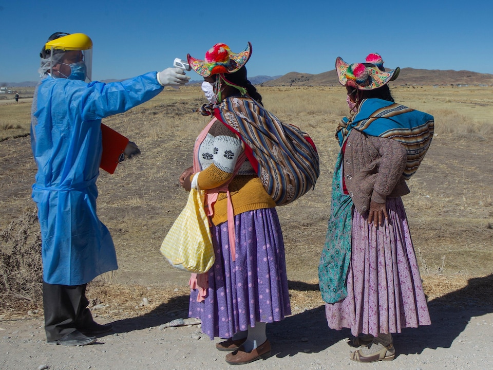 Deux femmes portant des chapeaux traditionnels attendent en file.