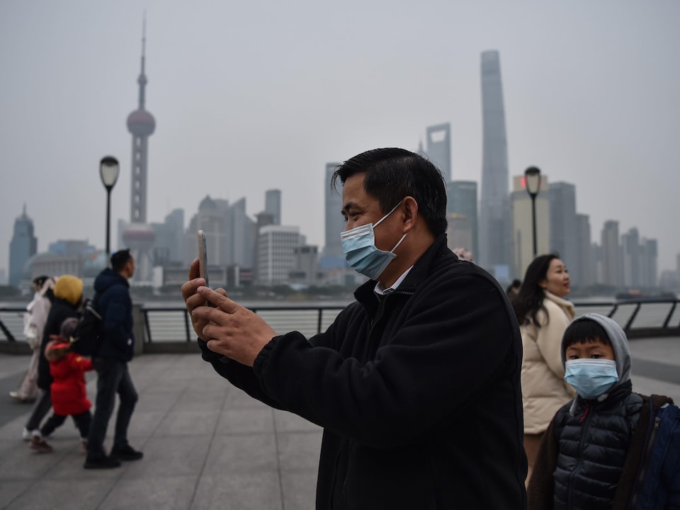Un homme portant un masque respiratoire fait un égoportrait à Shanghai.