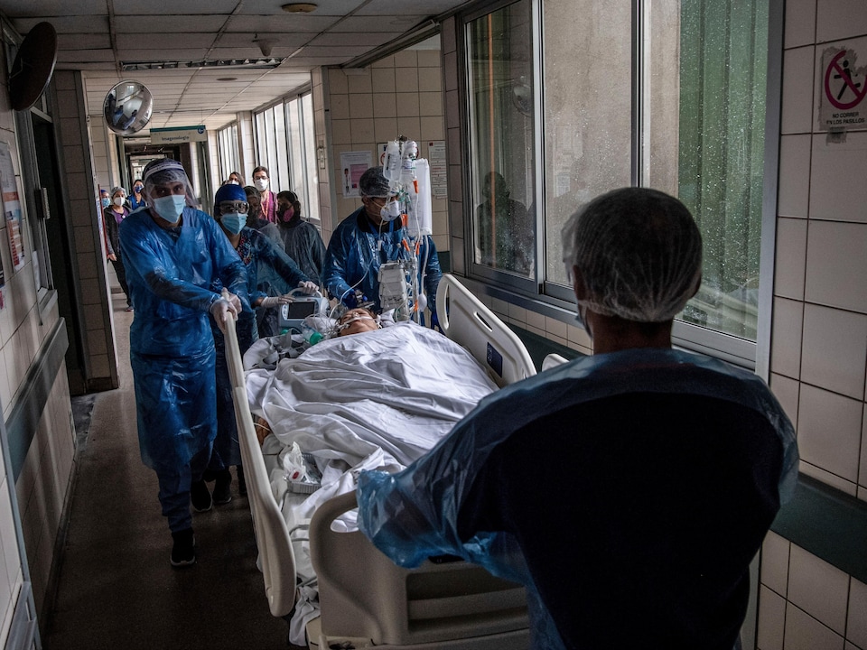 Un patient entouré d'infirmiers dans un couloir d'hôpital.