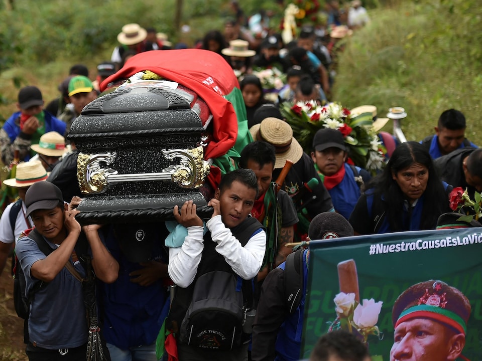Des Autochtones portent un cercueil, suivis par une procession.