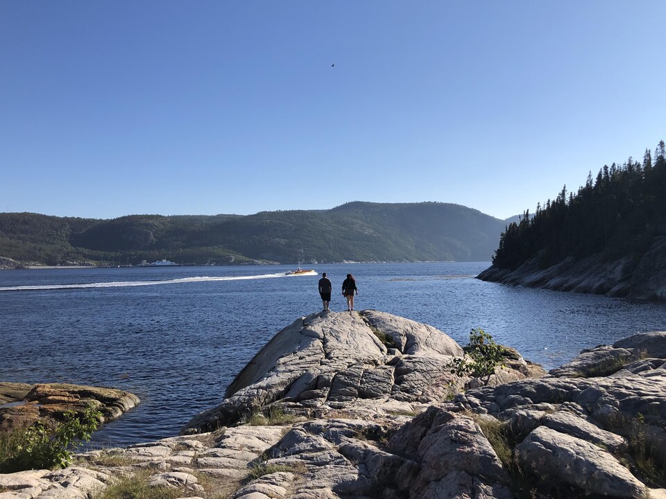 Un couple sur les rochers à l'embouchure du fjord du Saguenay.