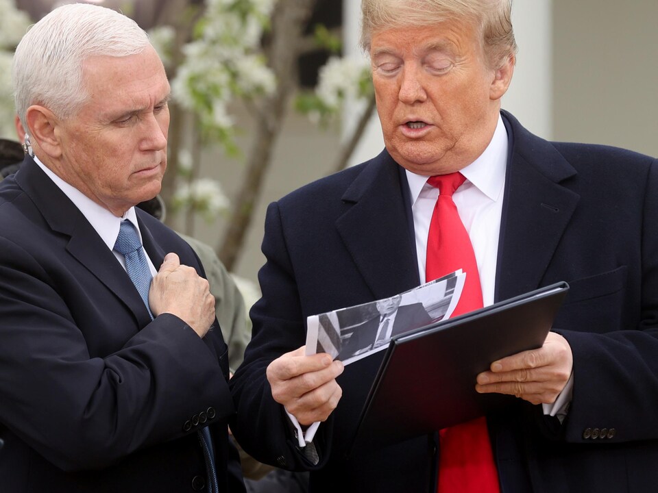 Donald Trump dit quelque chose à Mike Pence en lui montrant un document avant leurs interventions télévisées.