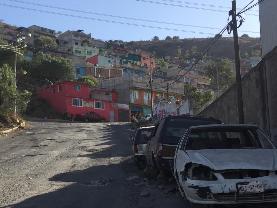 Des carcasses de voiture bordent une rue de la ville.