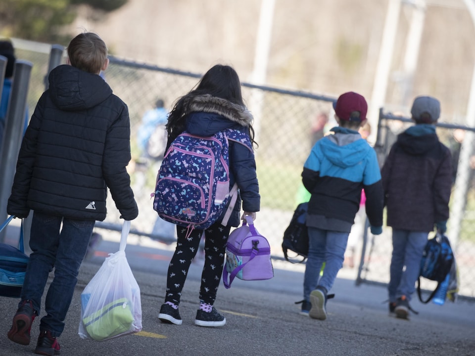 Des enfants gardent une bonne distance entre eux avant d'entrer dans une cour d'école.