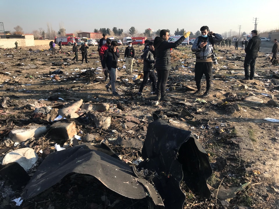 Des gens fouillent les débris au sol à la suite de l'écrasement d'un avion.