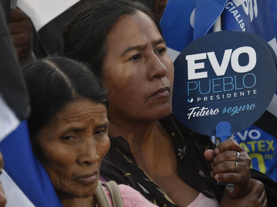 Une femme tient dans ses mains une pancarte sur laquelle est écrit « Evo peuple président ».