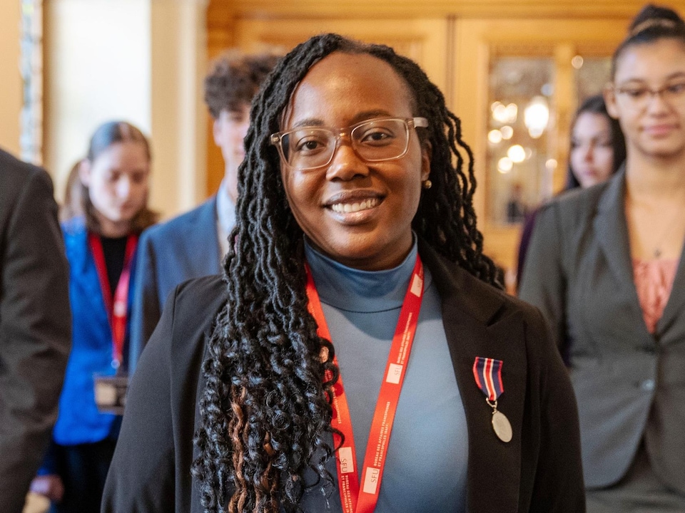 Blanche Monabeka au premier plan, avec derrière des personnes, dans un couloir du parlement jeunesse de Victoria, en Colombie-Britannique, en janvier 2026.
