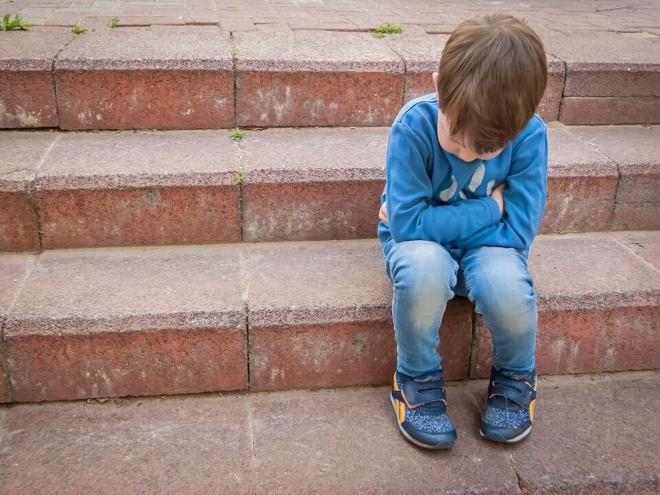 Un enfant est assis sur des marches.