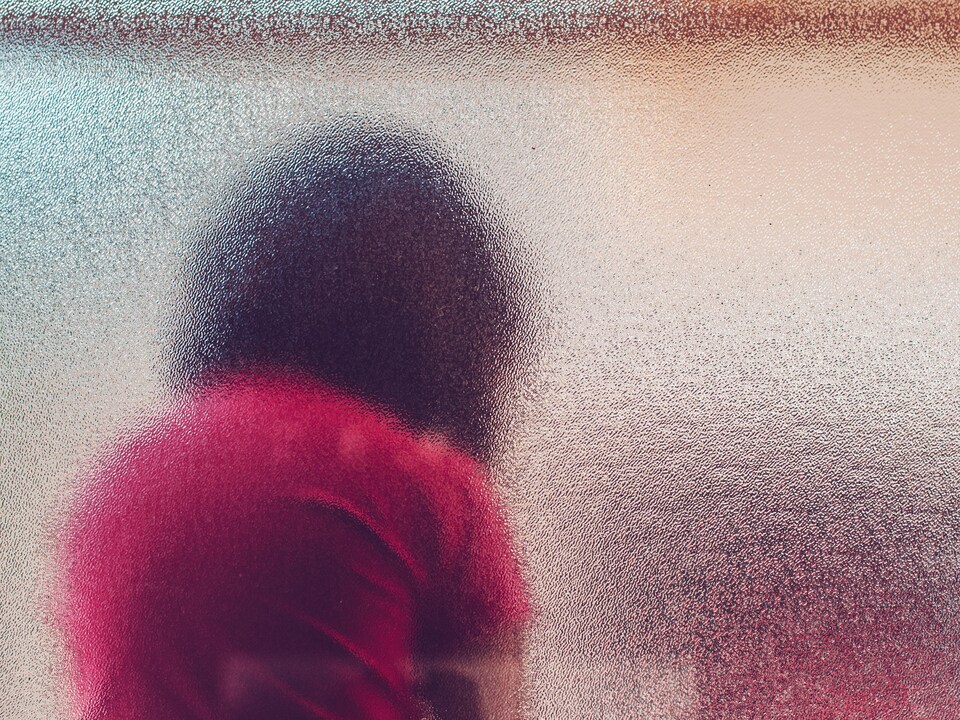 Un enfant regarde vers le bas derrière une vitre givrée (archives).