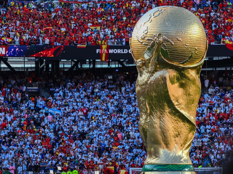 Le trophée de la Coupe du monde devant les gradins combles.