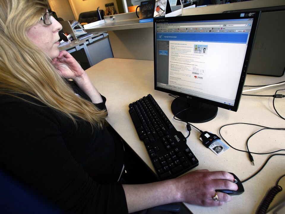 Une femme estonienne est assise derrière son ordinateur.