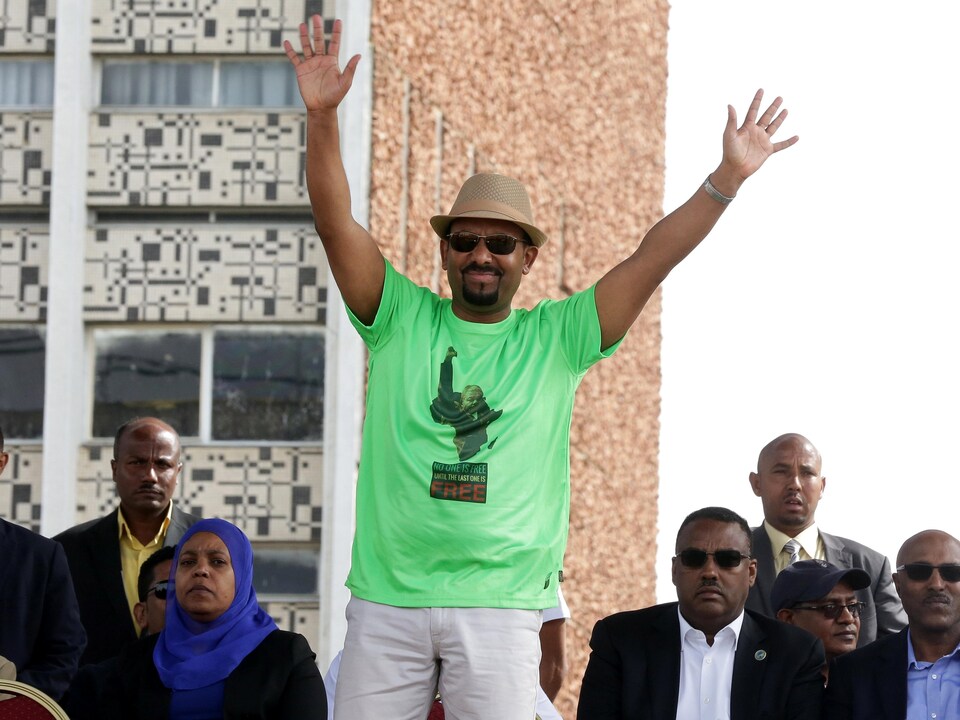 Vêtu d'un t-shirt vert et d'un chapeau, Abiy Ahmed lève les bras en l'air pour saluer la foule.