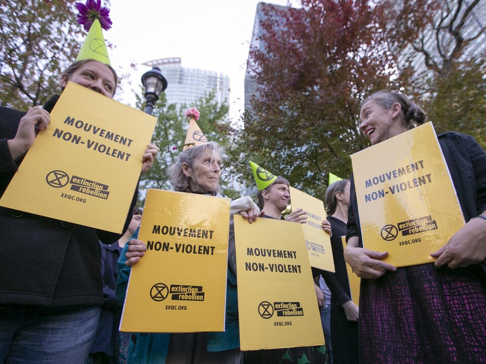 Des femmes portant un chapeau de fête tiennent des pancartes sur lesquelles est écrit : «Mouvement non violent ».
