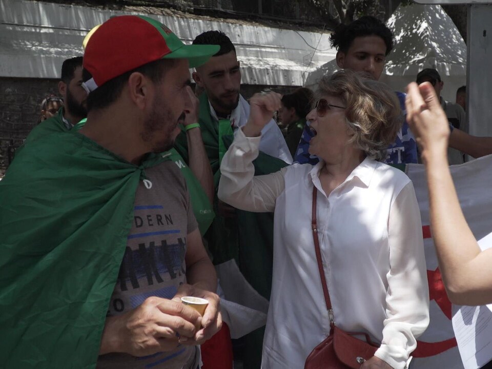 Fatma Oussedik scande un slogan, entourée de jeunes dans une manifestation.
