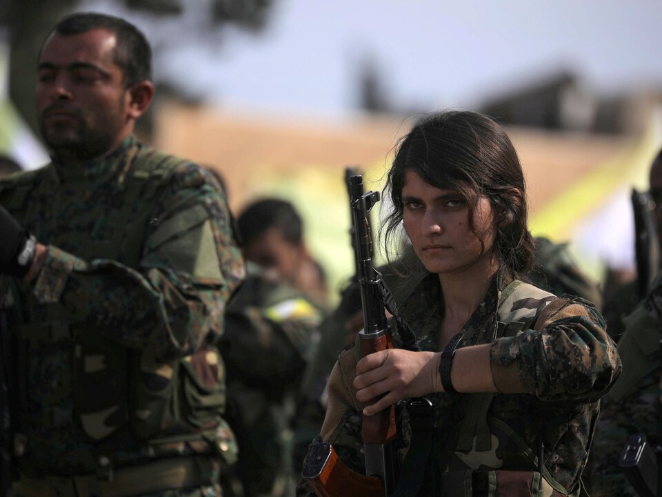 Une jeune combattante tient une arme.