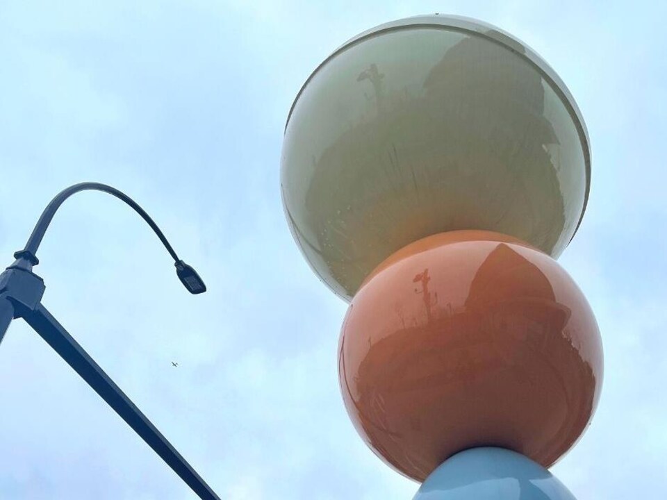 Trois boules superposées à côté desquelles se trouve un lampadaire.