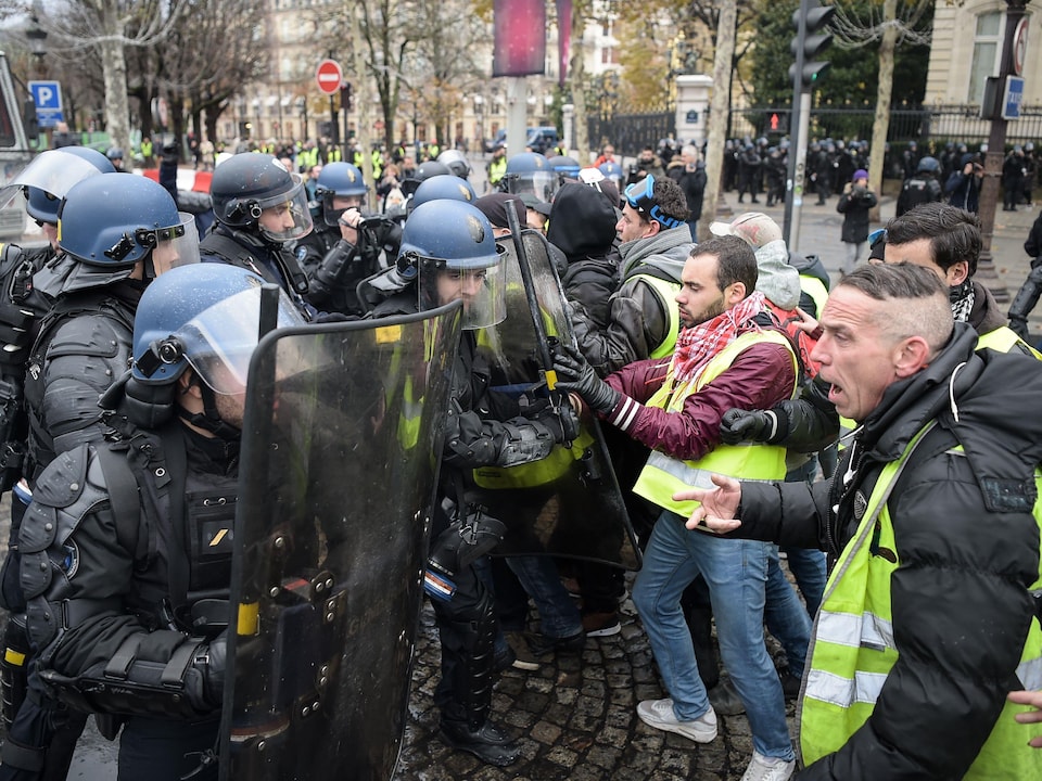 Des policiers antiémeutes font face à des manifestants en colère dans une rue.