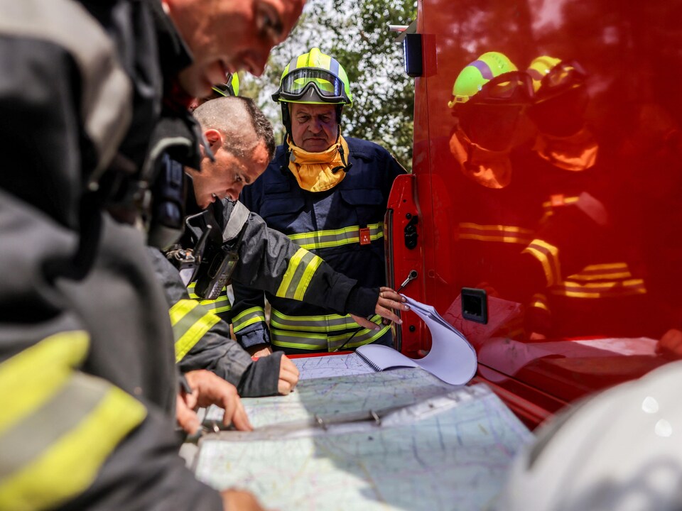 Un pompier autrichien regarde une carte à l'arrière d'un camion.