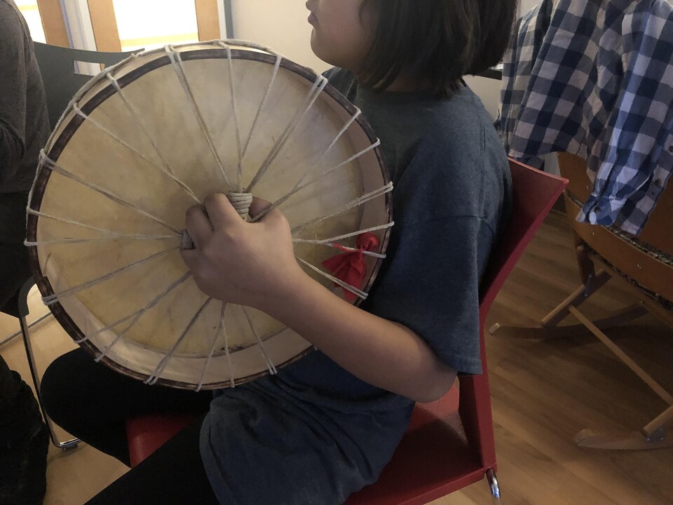 Un enfant tient un tambour.