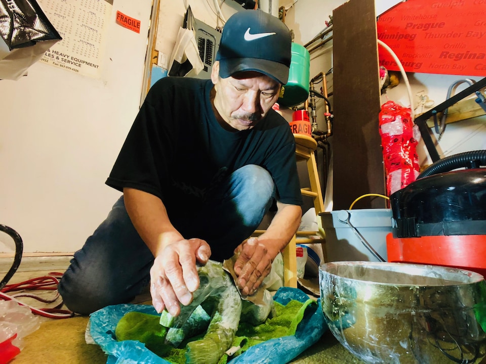 Un homme procède au polissage de sa sculpture.